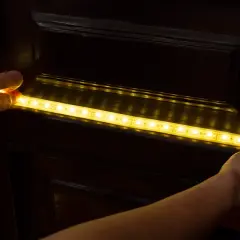 Montaż taśmy LED 12v na ciemnych meblach, tworząc subtelne oświetlenie w domu.