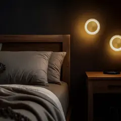 Dwie okrągłe lampki nocne oświetlają przytulną sypialnię. Ciepłe światło, choć nie wiemy, ile to lumenów, tworzy relaksującą atmosferę.
