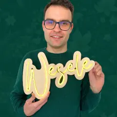 Uśmiechnięty mężczyzna prezentuje napis "Wesele" wykonany z drewna i taśmy LED. Dowiedz się, jak zrobić neon z taśmy LED!