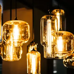 Jak czyścić szklany klosz lampy? Kilka wiszących lamp z bursztynowymi kloszami i widocznymi żarówkami.
