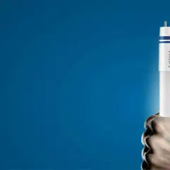 Dłoń trzyma nową żarówkę LED Philips, gotową do wymiany w tubie oświetleniowej.
