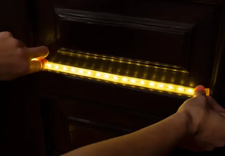 Montaż taśmy LED 12v na ciemnych meblach, tworząc subtelne oświetlenie w domu.
