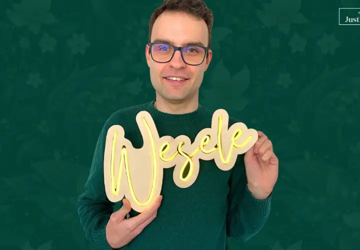 Uśmiechnięty mężczyzna prezentuje napis "Wesele" wykonany z drewna i taśmy LED. Dowiedz się, jak zrobić neon z taśmy LED!