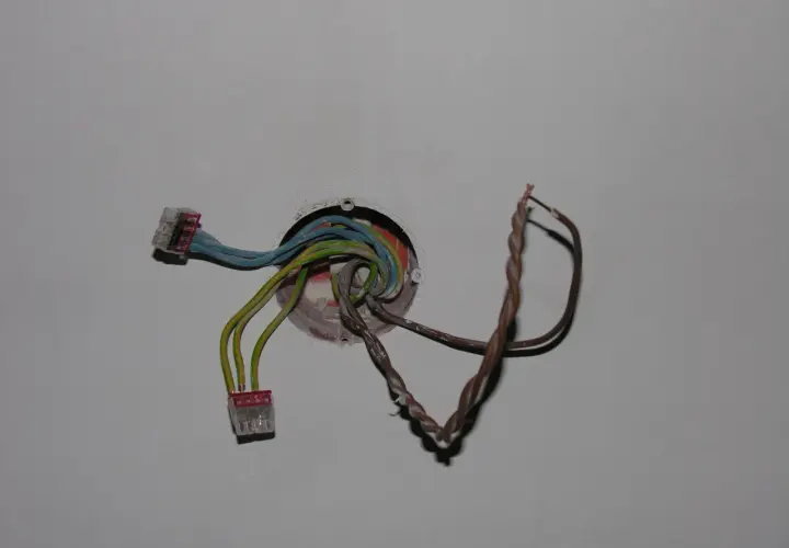 Instalacja elektryczna z kolorowymi przewodami w puszce, gotowa do podłączenia, aby zrobić dodatkowy punkt świetlny.