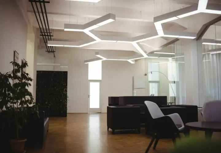 Nowoczesne biuro z designerskim oświetleniem. **LED zintegrowany co to znaczy?** To światło wbudowane w sufit, tworzące geometryczne wzory.