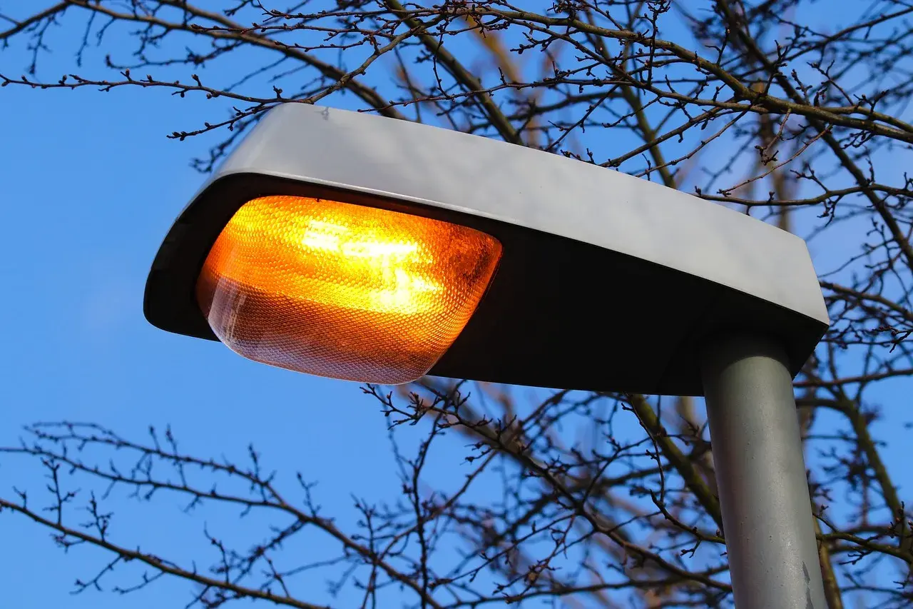 Pomarańczowa lampa uliczna świeci jasno, mimo że jest dzień. Awaria oświetlenia ulicznego?