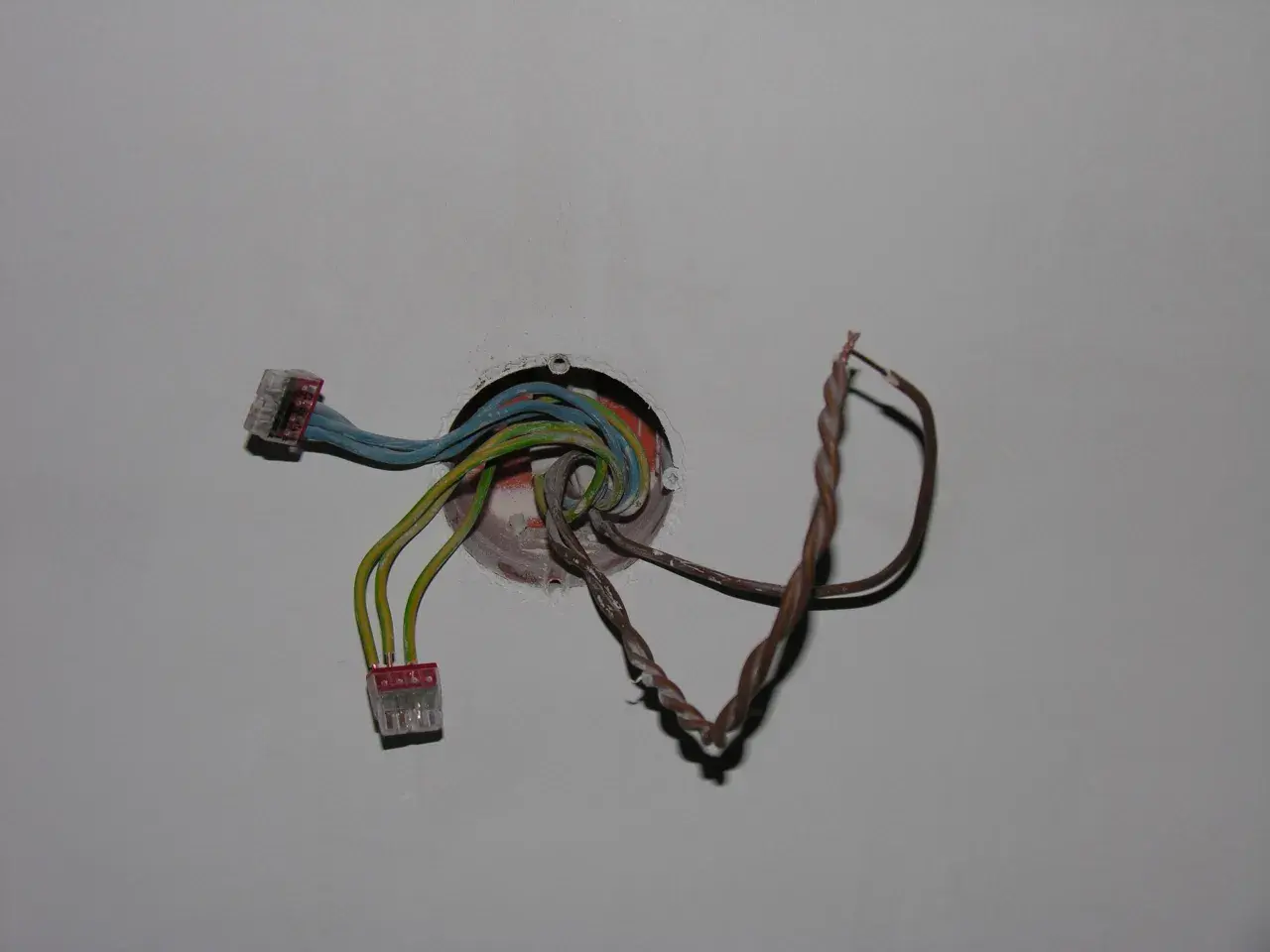 Instalacja elektryczna z kolorowymi przewodami w puszce, gotowa do podłączenia, aby zrobić dodatkowy punkt świetlny.