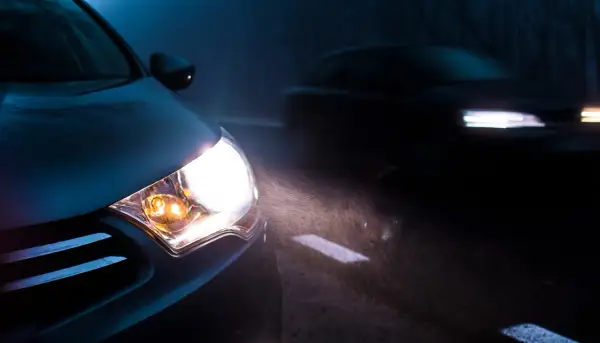 Mocna lampa led świeci jasno, rozświetlając mglistą drogę. W oddali widać inny samochód.