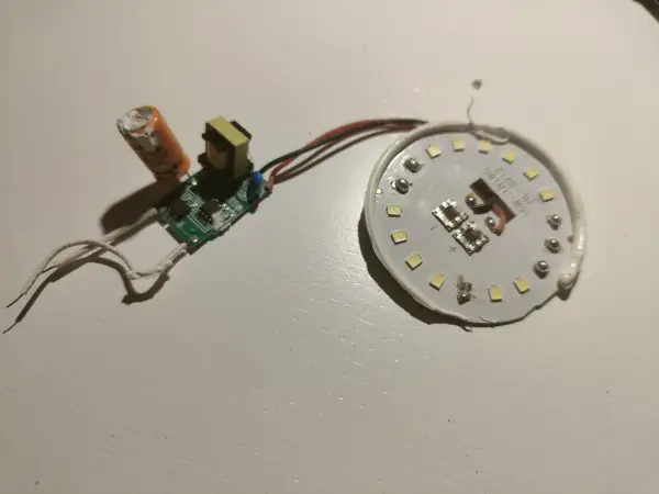 Rozłożona żarówka LED z widocznym modułem zasilania i płytką z diodami. Może to być pomocne, gdy zastanawiasz się, jak naprawić żarówkę LED.