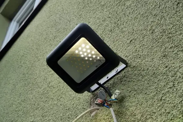 Nowa lampa led żarzy się po włączeniu, oświetlając zieloną ścianę.